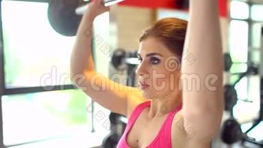 <strong>肌</strong>肉发达的女运动员穿着<strong>粉</strong>红色上衣在<strong>健身</strong>房锻炼举重。 <strong>健身</strong>女孩在<strong>健身</strong>房锻炼。 这就是